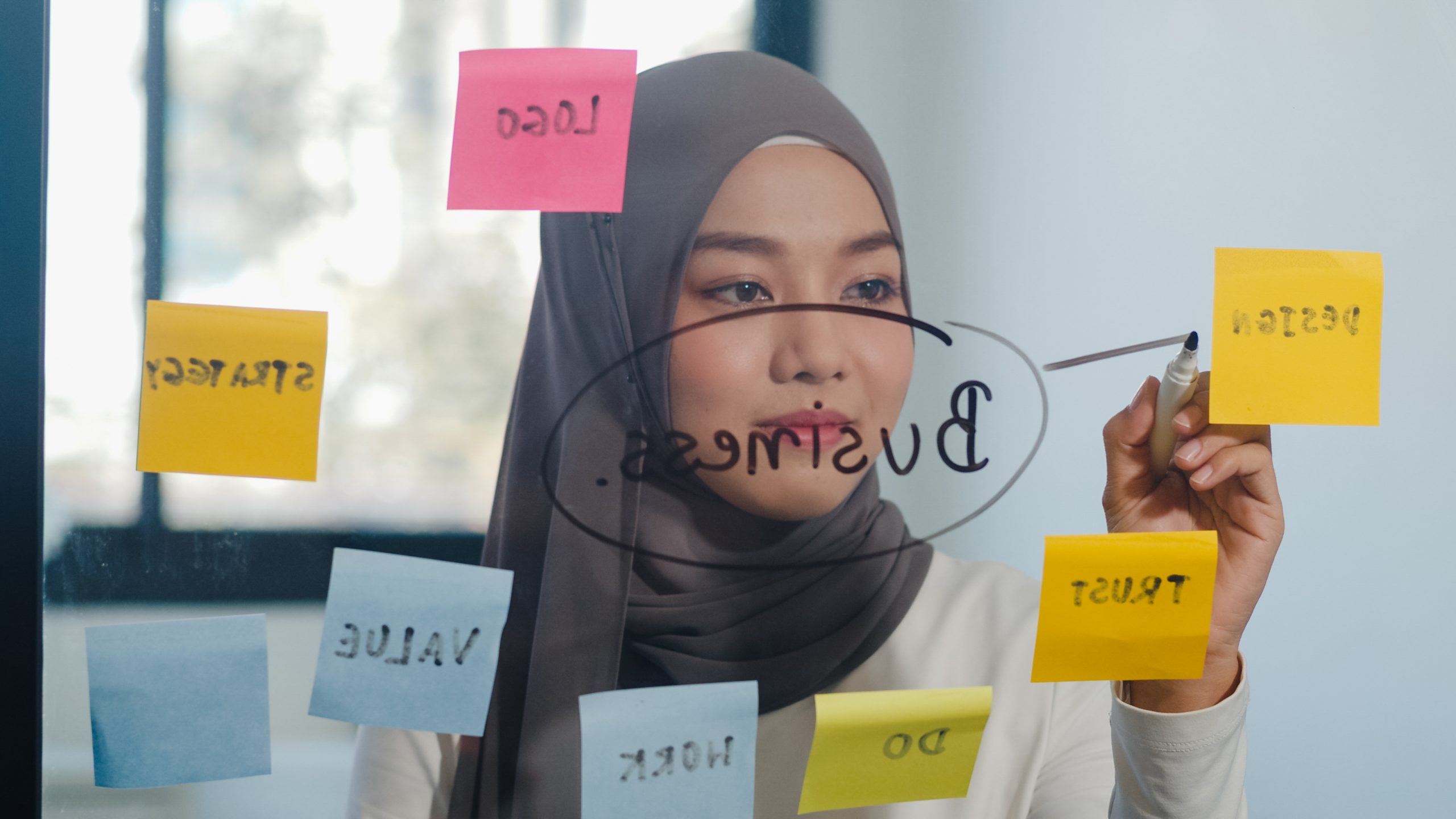 Asia muslim lady write information, strategy, reminder on glass Asia muslim lady write information, strategy, reminder on glass board in new normal office. Working from home, remotely work, self isolation, social distancing, quarantine for coronavirus prevention.